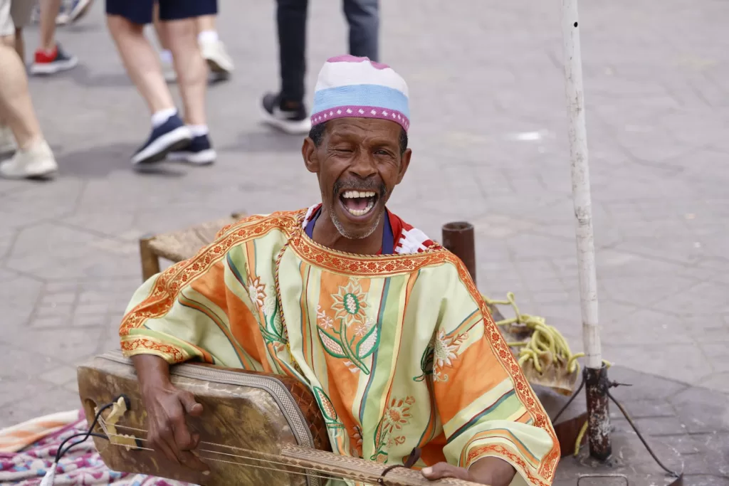 Musician in Traditional Moroccan Clothing Playing a Gnawa and Singing on a Street