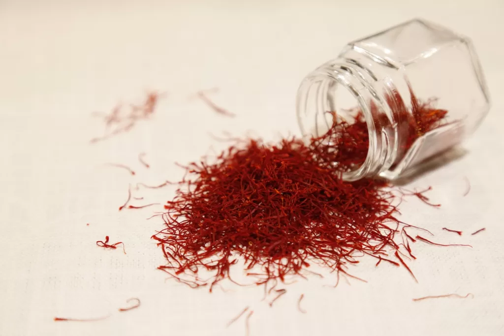 a glass jar filled with red Saffron  on top of a table